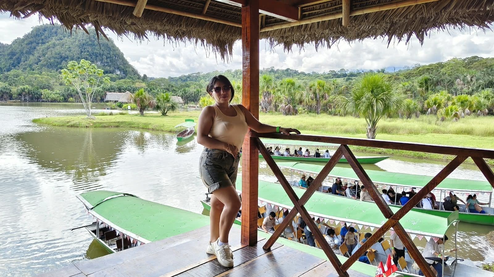 Visitante apoyada en la baranda de una terraza con vista a la laguna y a las lanchas verdes